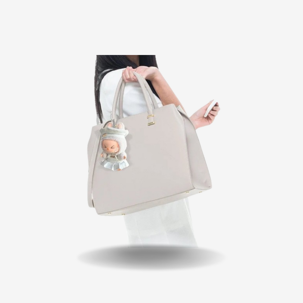 Look MIN – Robe & Chapeau figurine attachée à un sac à main beige.